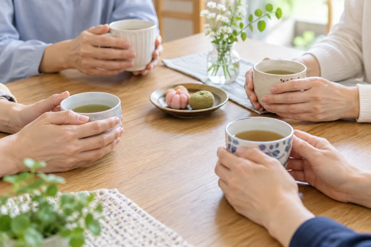 テーブルを囲んで湯のみを手にしている、大人たちの手元